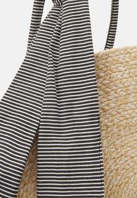 Borsa in paglia intrecciata con un corpo di un marrone chiaro testurizzato e un accento in tessuto a righe bianche e nere legato nella parte superiore.