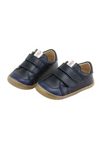 Zapatos para niño pequeño de color azul marino con suelas color camel, que presentan dos correas de velcro y punteras texturizadas sobre un fondo blanco.
