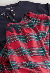 Navy long-sleeve top with wooden buttons paired with red and green plaid pajama bottoms featuring an elastic waistband and drawstring.