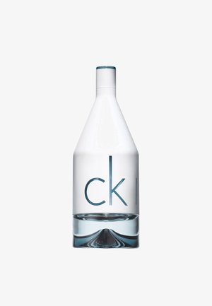 Kirkas lasipullo, jossa on kapeneva muoto, siniset yksityiskohdat ylhäällä ja kohokuvioitu teksti "ck" tyylikkäällä, modernilla fontilla.