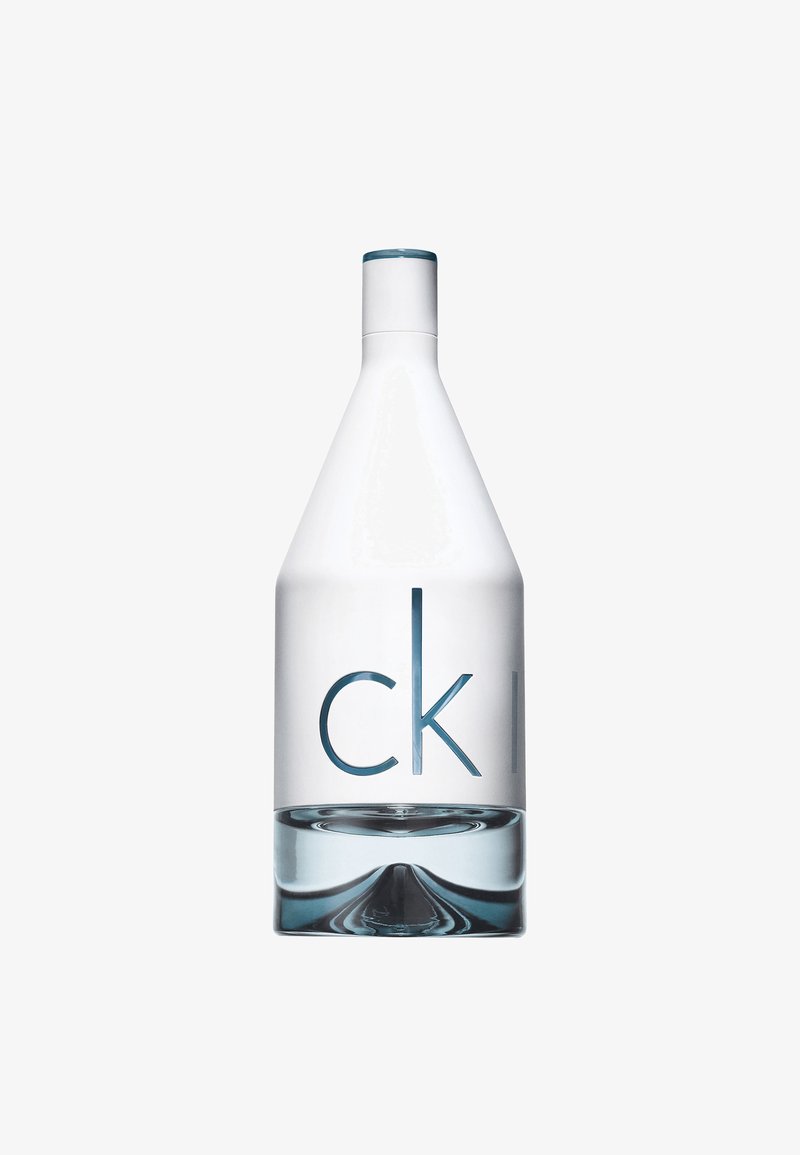 Kirkas lasipullo, jossa on kapeneva muoto, siniset yksityiskohdat ylhäällä ja kohokuvioitu teksti "ck" tyylikkäällä, modernilla fontilla.