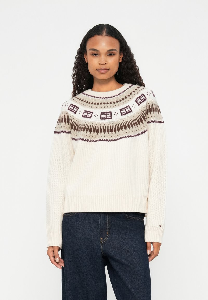 Ribbede cremede sweater med en mønstret yoke, der har brune og mørkerøde geometriske designs. Rund hals og løs pasform.
