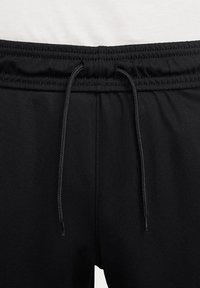 Zwarte sportshorts met een elastische tailleband en een trekkoord. De stof heeft een gladde textuur en een schoon, minimalistich design.