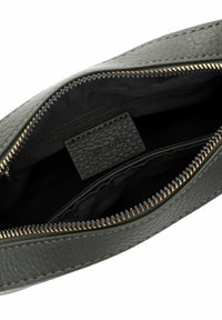 Borsa in pelle verde oliva con superficie texture, zip dorata e fodera in tessuto nero. Include un'etichetta interna con il logo "Tamaris".