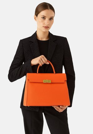 Oranje leren handtas met een gestructureerd ontwerp, voorzien van een bovenhandgreep en een gouden sluiting. De textuur is glad met een matte afwerking.