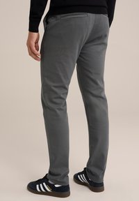 Chino gri cu o croială slim, realizat dintr-un material moale. Dispune de un buzunar pe spate și este asortat cu adidași negri care au dungi albe.