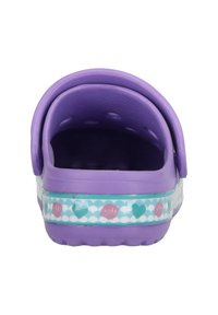 Lila Clogs mit einem strukturierten Innenraum, einem Rückriemen und einem dekorativen Band mit Muschelmustern in Pink, Teal und Weiß.