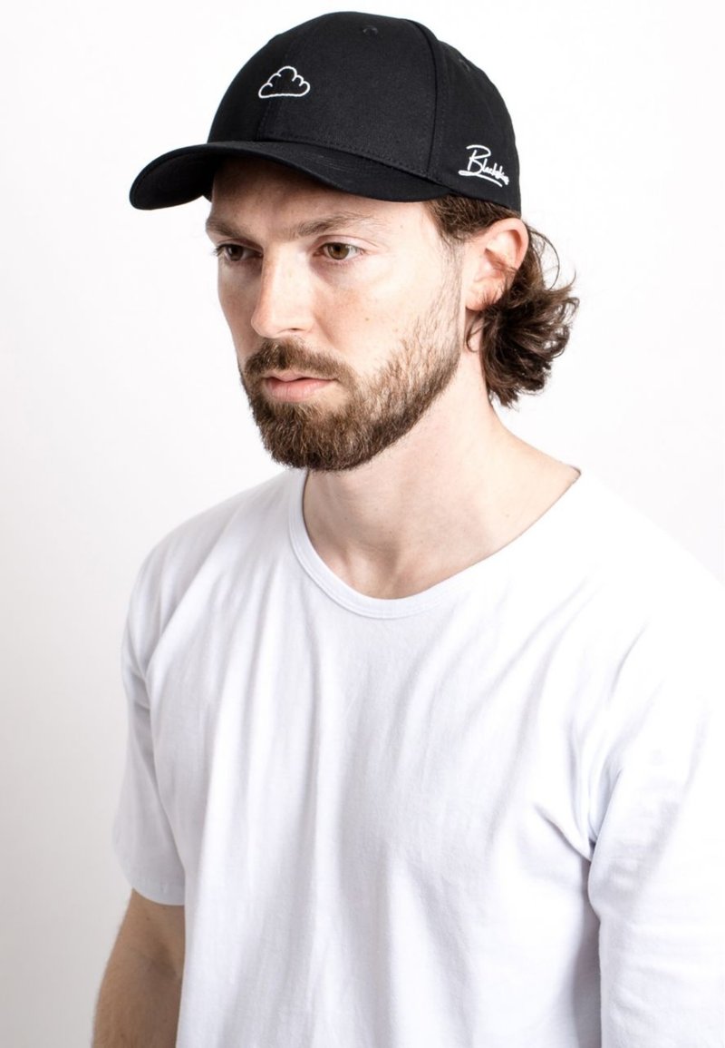 Black cap with white cloud design on front and script logo on the side, worn with a plain white t-shirt. Fabric appears smooth and structured.