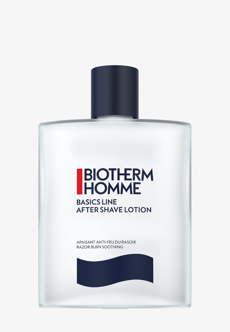 Bouteille rectangulaire transparente de lotion après-rasage avec un capuchon bleu marine. L'étiquette comprend du texte rouge et noir sur un fond blanc. Présente un design de vague bleue.