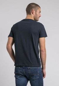 T-shirt à manches courtes gris foncé vu de dos. Tissu doux et lisse avec un col rond et sans motifs ni embellissements visibles.