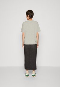 Lys grå kortermet skjorte med rund kant, kombinert med en lang svart denimskjørt og joggesko med grønne detaljer.