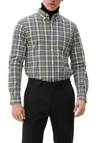 Camicia a quadri gialla e blu navy con colletto alla button-down, maniche lunghe e taglio sagomato, abbinata a pantaloni neri.