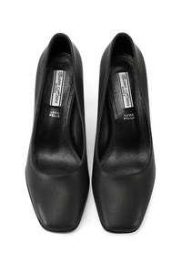 Scarpe nere in pelle con tacco alto e design a punta quadrata, caratterizzate da una superficie liscia e uno stile minimalista. L'interno mostra l'etichetta "Vera Pelle".