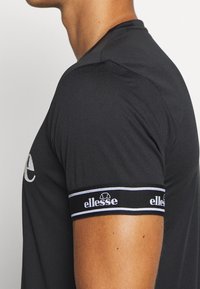 Kortärmad svart sportt-shirt med en åtsittande design. Har ett varumärke längs ärmen i vitt och blåa accenter.