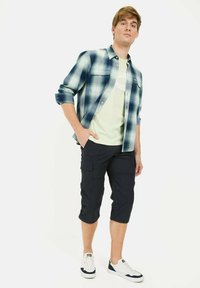 Green and blue plaid shirt, light green t-shirt, navy cargo shorts, white sneakers. Casual fit, short sleeves, buttons on the shirt.