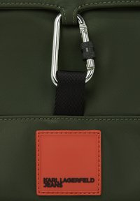 Πράσινη υφασμάτινη τσάντα με ασημένιο καραμπίνερ και πορτοκαλί δερμάτινη ετικέτα με ανάγλυφο το "KARL LAGERFELD JEANS" σε μαύρο χρώμα.