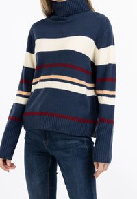 Neulottu pooloneule, jossa on laivastonsinisiä, kermaisia ja viininpunaisia raitoja. Ominaisuuksiin kuuluu resorit hihansuuissa ja helmassa, valmistettu pehmeästä langasta, rento istuvuus.