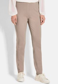 Beige aansluitende broek gemaakt van rekbare stof met een gladde textuur. Heeft een schone tailleband en zijnaden voor een gepolijste uitstraling.