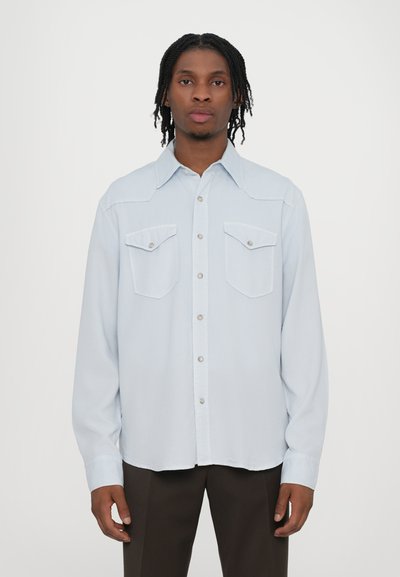 Hellblauses Langarmshirt mit Knopfleiste, zwei Brusttaschen und einem westernähnlichen Yoke-Design. Glatte Stofftextur.