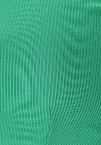 Tessuto verde texturizzato con righe verticali, che presenta un design senza cuciture. Dettaglio di cucitura notevole vicino al centro.