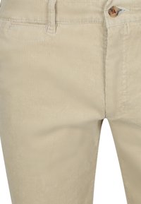 Beige corduroybroek van voren met zichtbare knoop, riemlus, voorzak en verticale geribbelde stoftextuur.