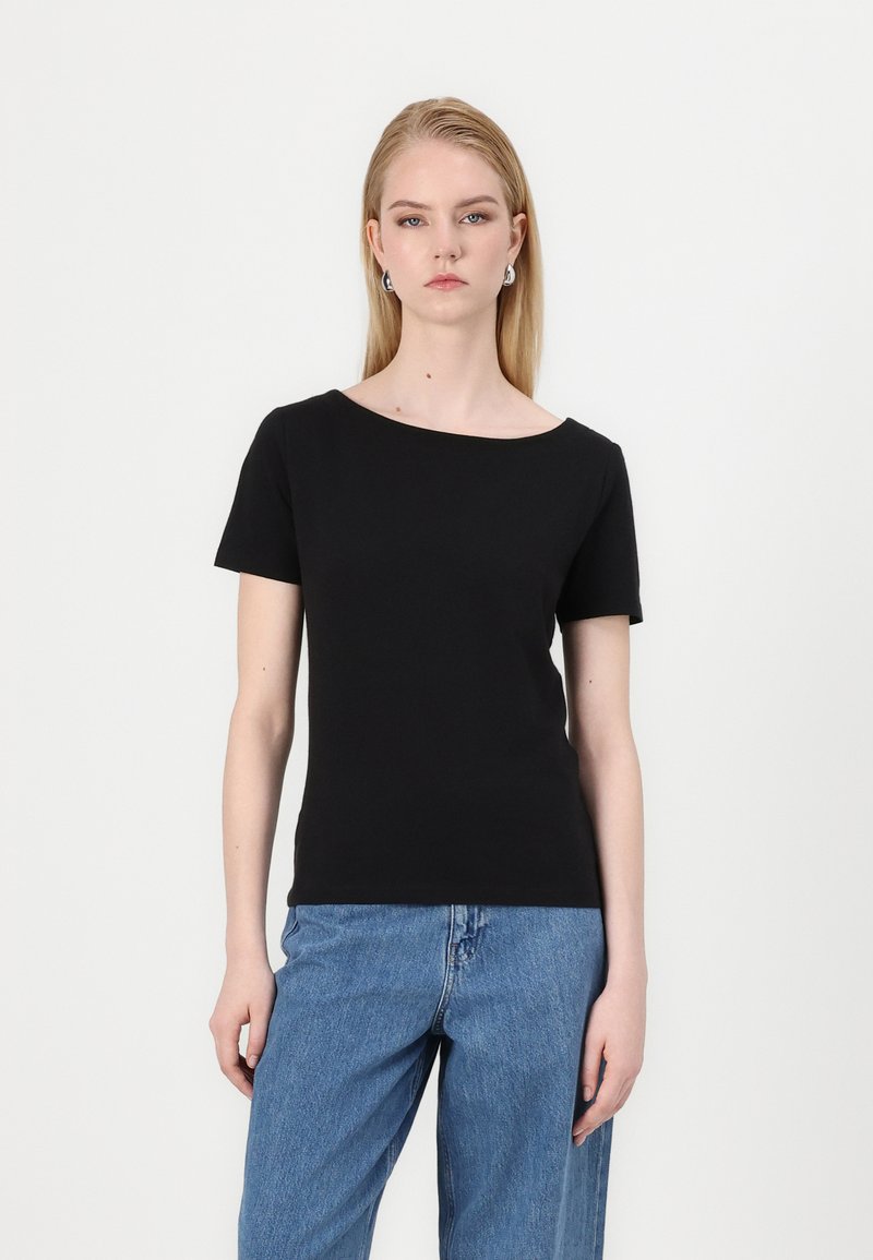 Svart kortärmad t-shirt med båtutskärning, tillverkad av ett mjukt material. Matchad med ljusblå högmidjade jeans i avslappnad passform.