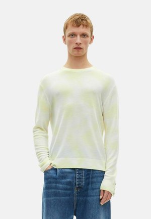Heller gelber Strickpullover mit rundem Ausschnitt und langen Ärmeln. Hat eine dezente Textur und einen gerippten Saum. Wird mit blauen Jeans getragen.
