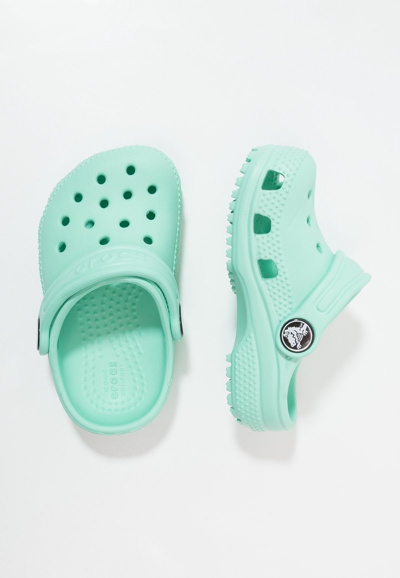 Lichtgroene Crocs in mintkleur met geperforeerd ontwerp, gladde textuur en een achterband. Voorzien van een opvallend logo en een gestructureerde zool voor grip.