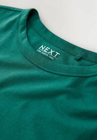 Grünes langärmeliges Crew-T-Shirt aus glattem Stoff. Verfügt über einen gerippten Rundhalsausschnitt und ein Etikett mit "NEXT" und Pflegehinweisen.