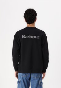 Zwarte sweatshirt met ronde hals, met een groot grijs "Barbour" logo op de achterkant. Gemaakt van stof met een gladde textuur.