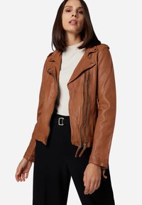 Braune Leder-Motorradjacke mit einem vorderen Reißverschluss, schrägen Revers und Reißverschlusstaschen. Texturierte Oberfläche mit taillierter Passform.