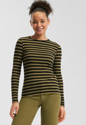 Long-sleeve top in olive green with black horizontal stripes. Ribbed texture, round neckline, fitted design. Paired with olive corduroy pants.