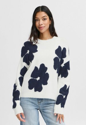 White oversized sweater with navy floral pattern, featuring ribbed cuffs and hem. Soft texture, relaxed fit, and round neckline.