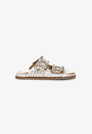 Tkané metalické skluzné sandály v odstínech zlaté a béžové, s dvěma př oversized sponami zdobenými čirými rhinestones. Texturovaná podrážka.