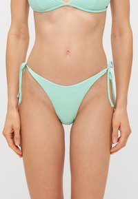 Mintgrønne bikini-bukser med ribbet tekstur, med sidesnøring for justerbar pasform og moderat dækning. Glat, letvægtsstof.