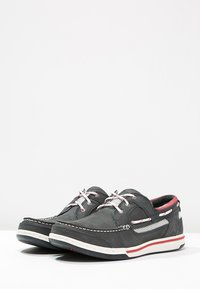 Graue Lederschiffsschuhe mit weißen Akzenten, rotem Innenfutter und gemusterten Schnürsenkeln. Verfügt über gestickte Details und eine leichte Sohle.