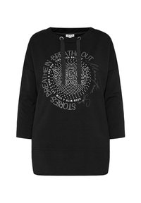Sudadera negra de corte holgado, con cuello redondo, capucha con cordón y lettering decorativo plateado con tachuelas en un patrón circular.