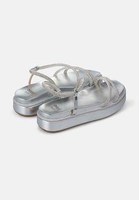 Sandali platform in argento con fascette incrociate testurizzate, finitura metallizzata e soletta imbottita, dotati di punta arrotondata e tacco basso.