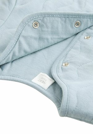 Világoskék steppelt anyag, patentgombokkal. Puha textúra, lekerekített élek, és egy jól látható "NEXT baby" felirat.