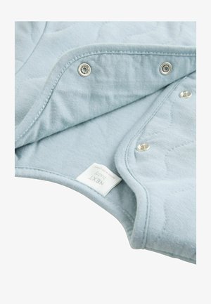 Světle modrá prošívaná látka se zapínáním na patentky. Měkká texture, zaoblené okraje a jasně viditelná nálepka s nápisem „NEXT baby“.
