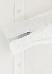 Weißes Langarmhemd mit Button-Down-Kragen, ausgestattet mit perlenartigen Knöpfen, strukturiertem Stoff und doppelt genähten Manschetten.