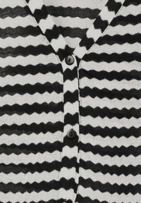 Černobíle pruhovaný cardigan s výstřihem do V, vlnitým vzorem a třemi černými knoflíky na přední straně, vyrobený z texturované pleteniny.