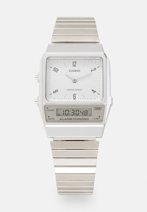 Srebrny zegarek Casio z prostokątną białą analogową tarczą, czarnymi znacznikami godzinowymi i wyświetlaczem cyfrowym. Metalowa bransoleta o szczotkowanej powierzchni. Wodoodporny.