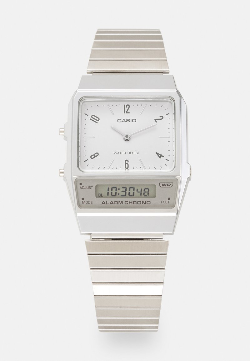 Montre Casio argentée avec un cadran analogique rectangulaire blanc, des index horaires noirs et un affichage numérique. Bracelet en métal avec finition brossée. Résistante à l'eau.