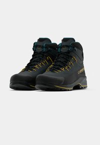 Melni augstpapēžu pārgājienu apavi ar pelēkiem akcentiem, ar strukturētu audumu, dzeltenām auklām un rakstainu gumijas zoli.