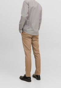 Grå och vit rutiga skjorta med lång ärm, parat med tan slim-fit byxor och svarta snörskor. Enkel, ren design.