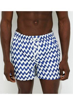 Męski tors ubrany w niebiesko-białe kąpielówki w falisty wzór z białym sznurkiem zawiązanym w pasie.