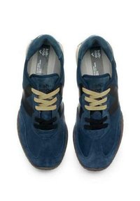 Sneaker blu in suede con lacci beige, accenti neri e una suola testurizzata. Presenta una punta arrotondata e un design con suola imbottita.