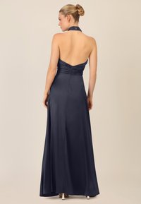 Navy Halterkleid mit tailliertem Oberteil, Raffung im Rücken und fließendem Rock. Hergestellt aus glattem, satinähnlichem Material.