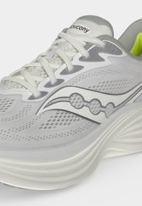 Ανοιχτό γκρι αθλητικό παπούτσι Saucony με λευκές και πιο σκούρες γκρι λεπτομέρειες, ορατά κορδόνια και μαλακό πέλμα.